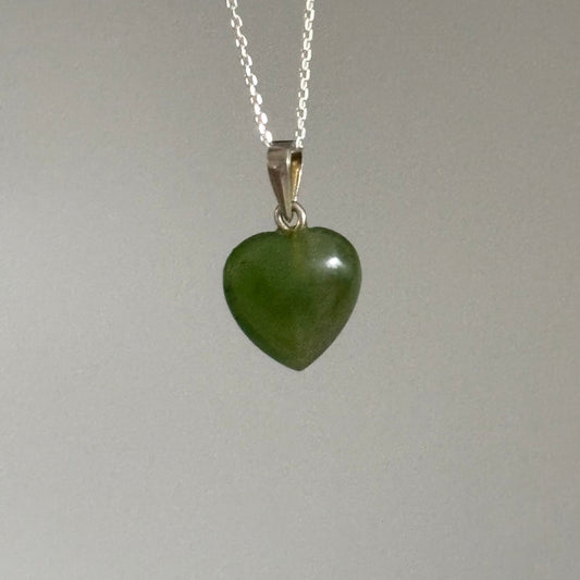 Necklace with a green heart-shaped pendant on a plain background