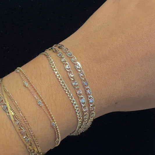 Close-up of a wrist wearing multiple gold bracelets on a black background