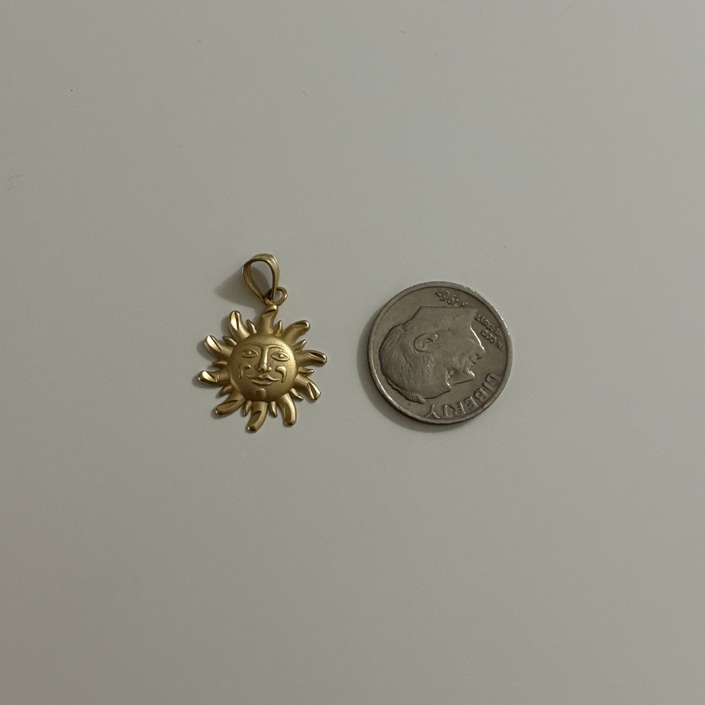 Gold sun-shaped pendant and silver coin on a white background