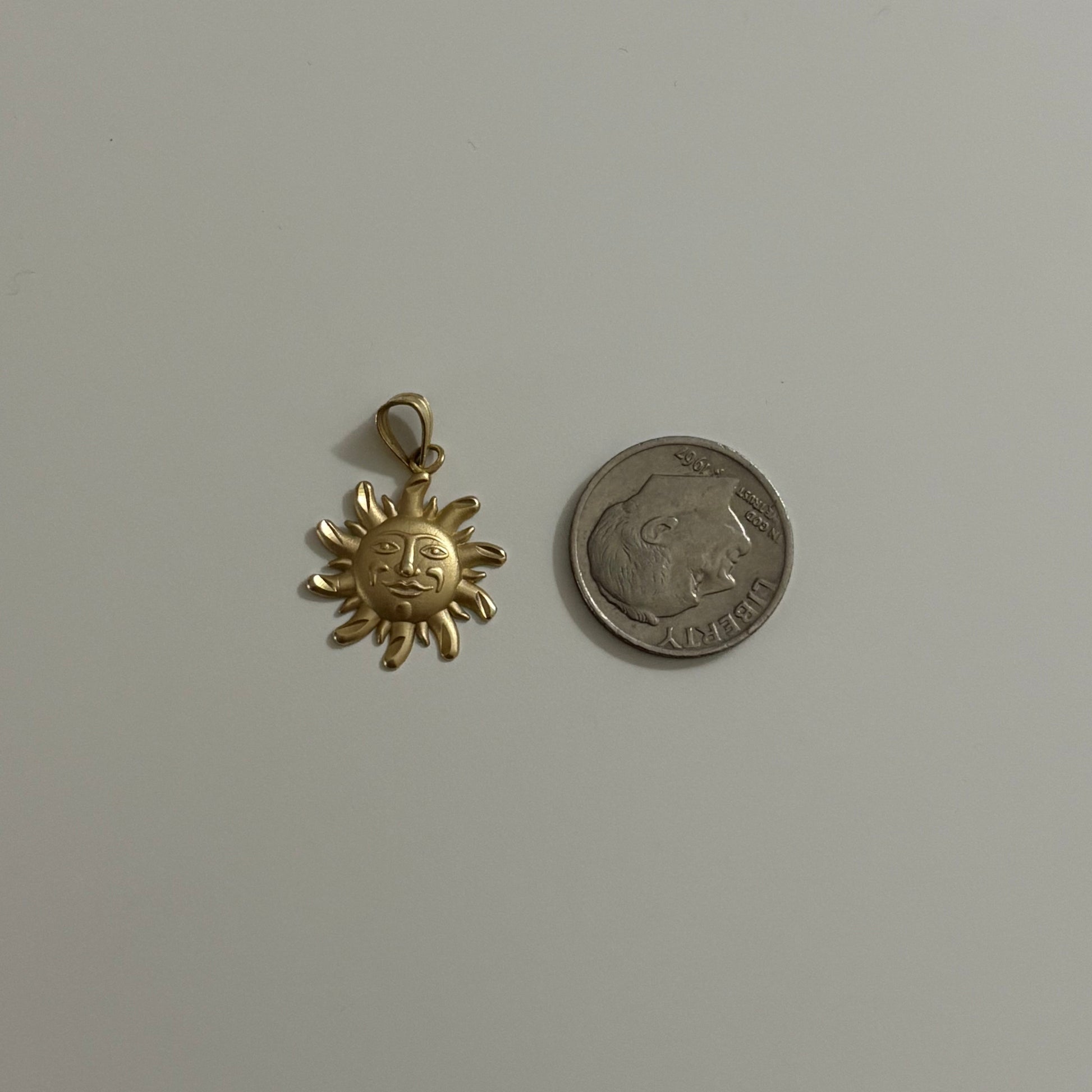 Gold sun-shaped pendant and silver coin on a white background