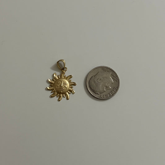 Gold sun-shaped pendant and silver coin on a white background