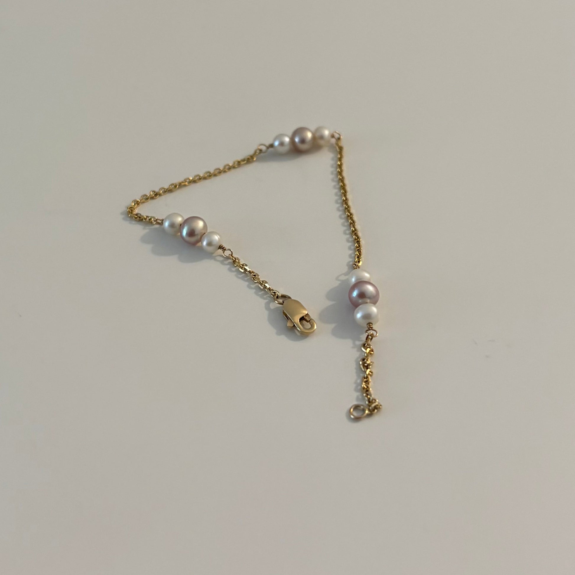 Gold chain with pearls on a white surface