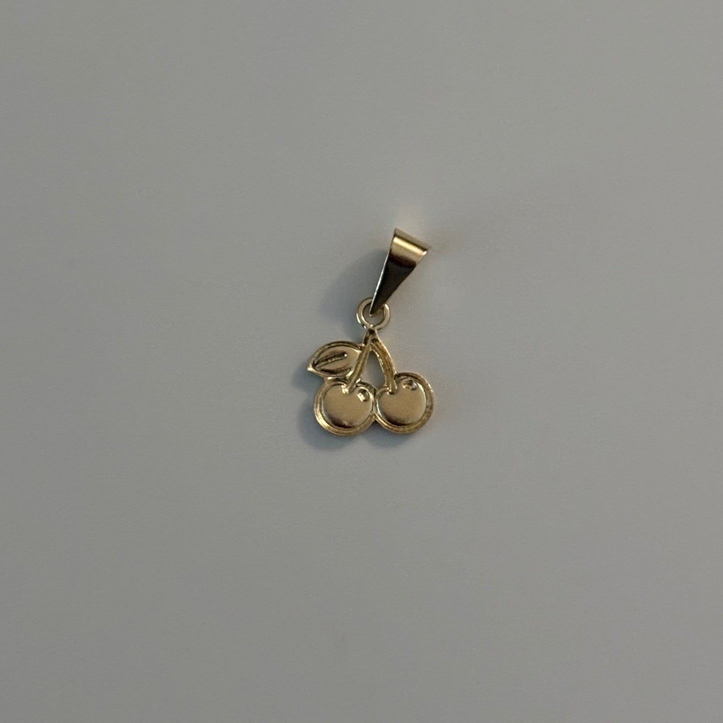 Gold cherry-shaped pendant on a gray background