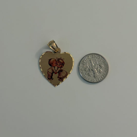 Two heart-shaped gold pendants with red stones on a gray surface, one next to a silver coin for size comparison.