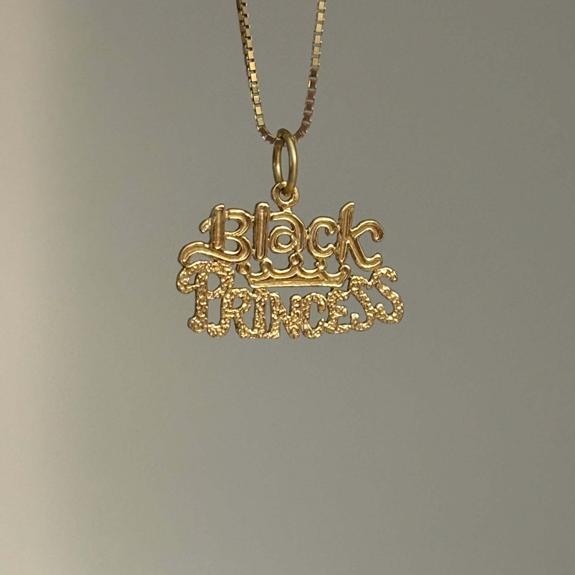 Gold necklace with black princess  pendant on a gray background