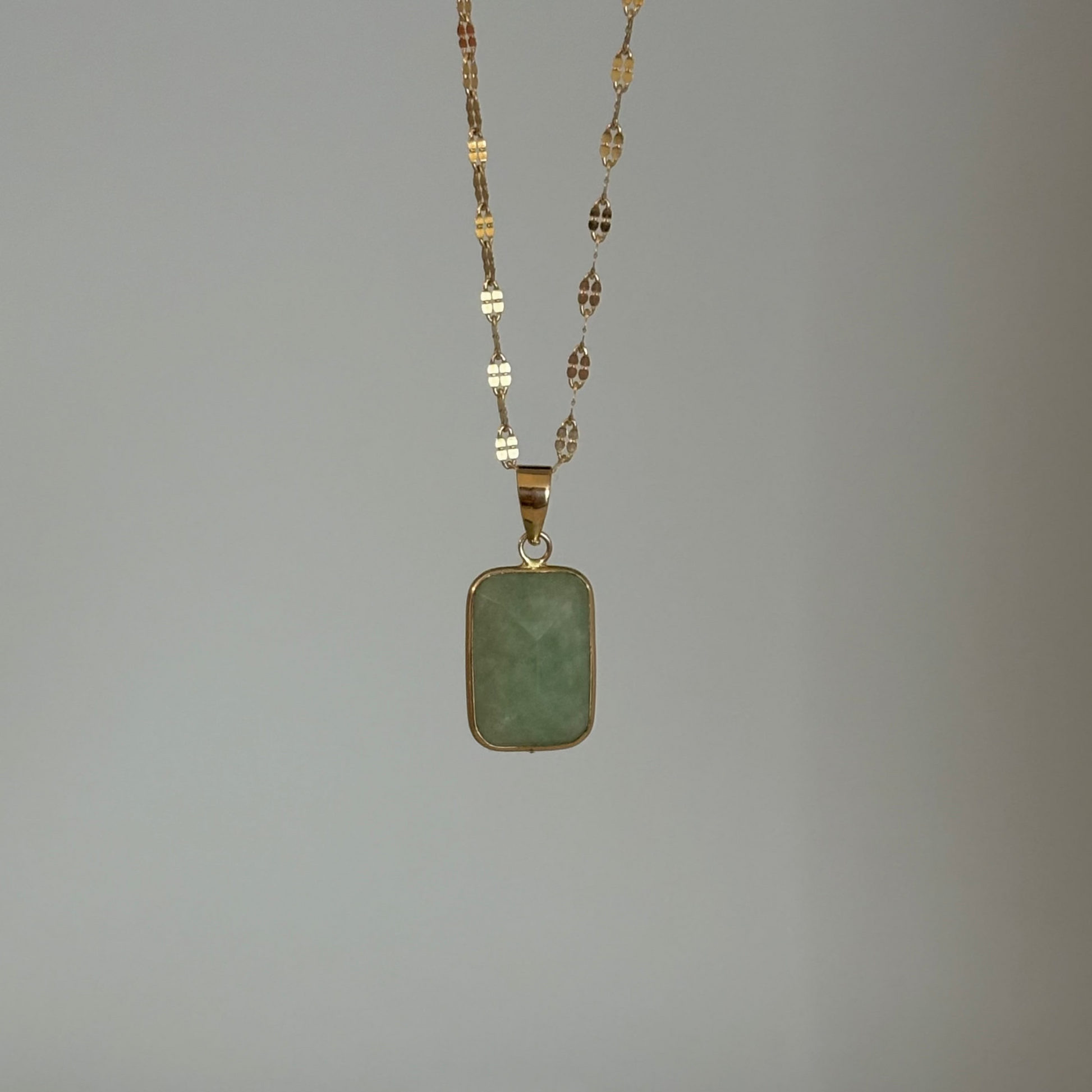 Necklace with a green pendant on a plain background