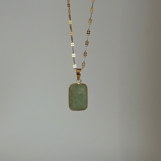 Necklace with a green pendant on a plain background